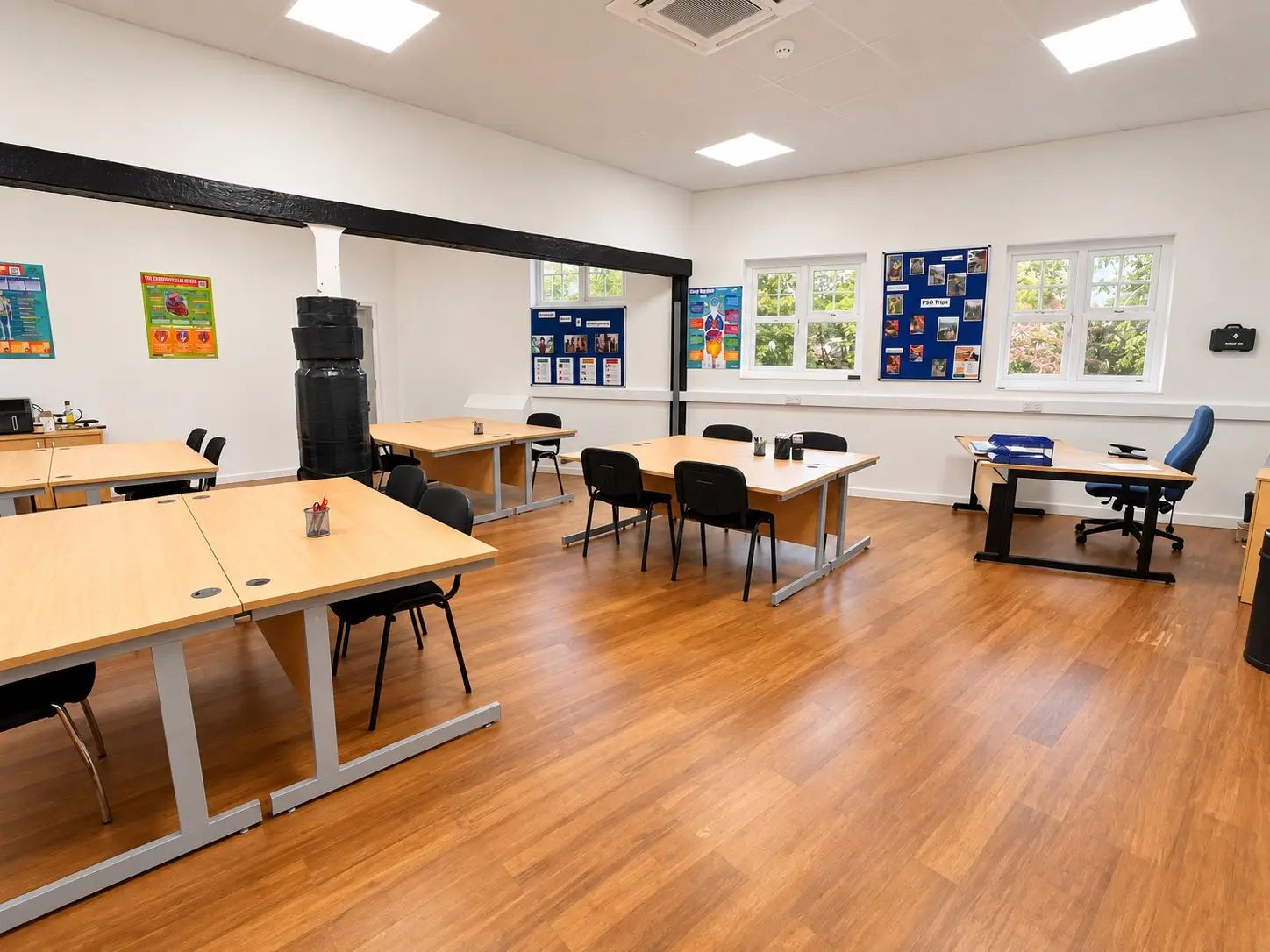 A Waterfront classroom with desks grouped for teaching, wall displays and a punch bag beside the door